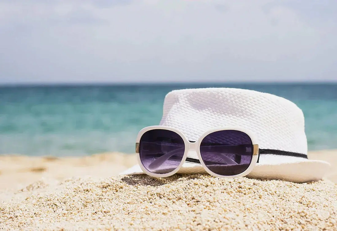 Beautiful cat eye glasses in white on sand with a hat by the beach, available in various colors